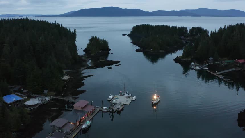 Aerial of a bay with a fishing boat near a small village dock at dusk