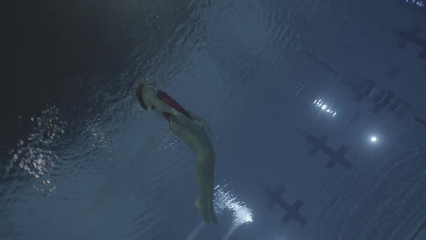 A diver swimming up to the surface in a deep pool
