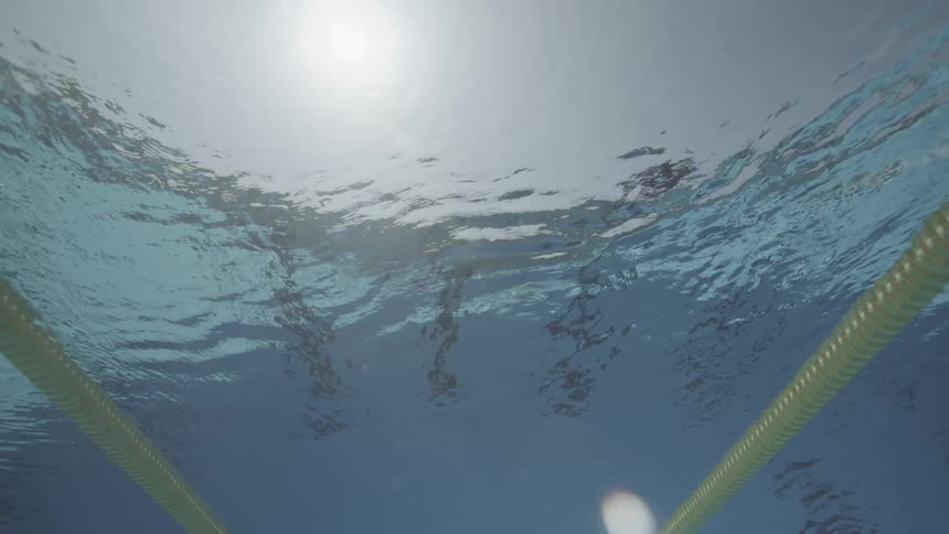 Underwater view of sun rays shining on an outdoor swimming pool