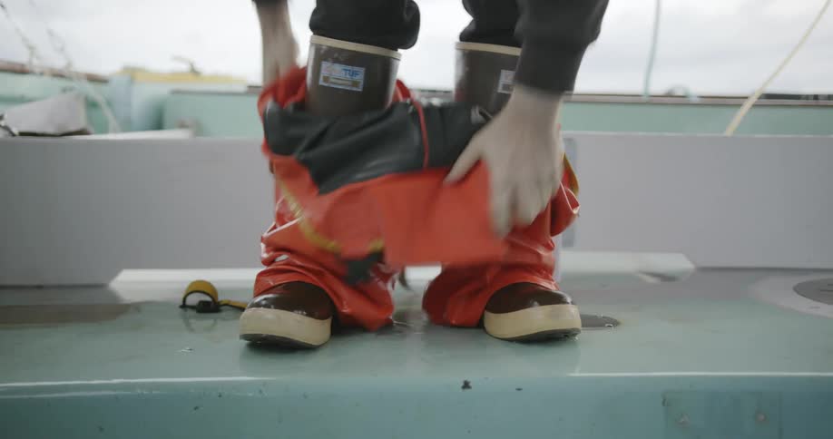 A fisherman pulls up his rubber overalls