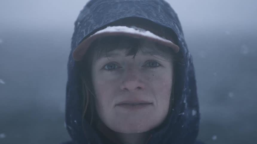 A woman smiling wearing a hat in a blizzard