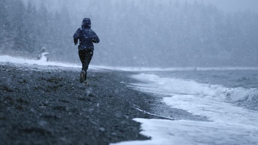 A person running on the beach during a blizzard