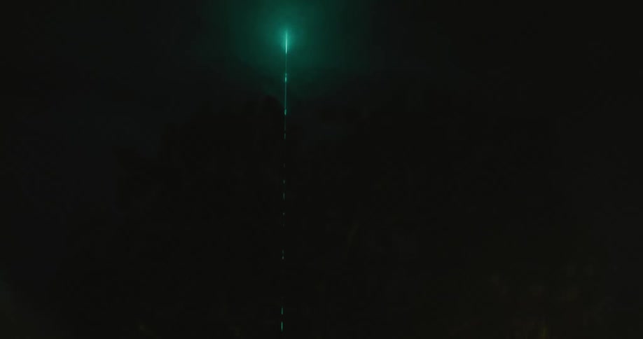 A radio tower glows with blue light at night