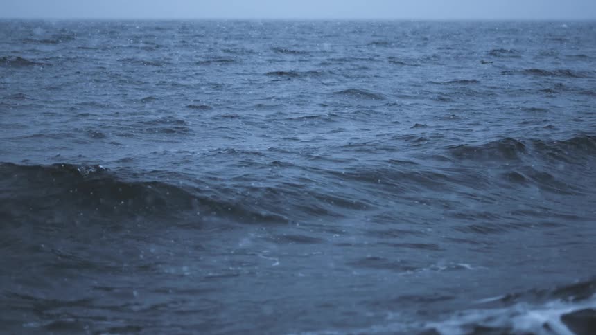 Waves in the ocean move in slow motion as snow falls