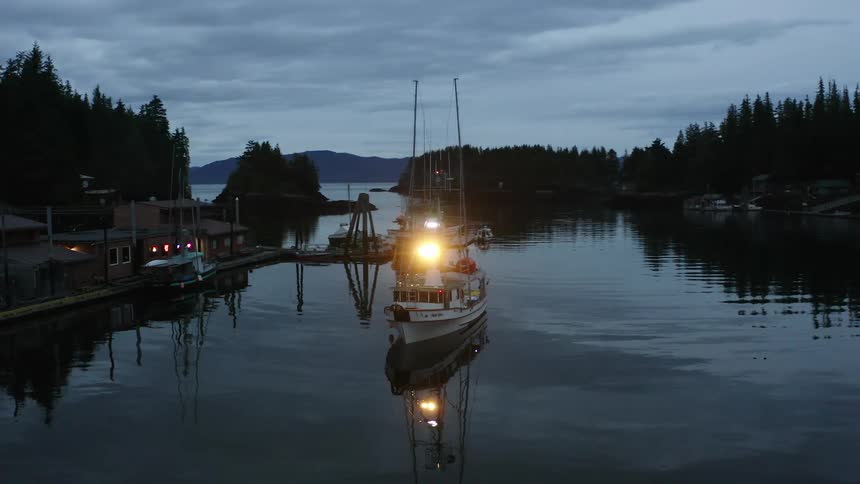 Fishing boat enters a harbor at dusk
