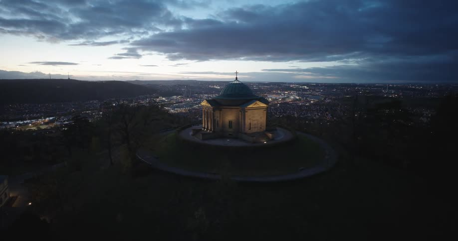 A mausoleum the sepulchral chapel on a mound hill wrttemberg hill overlooking a large city stuttgart germany at dusk with dark clouds in a partially lit sky in the background