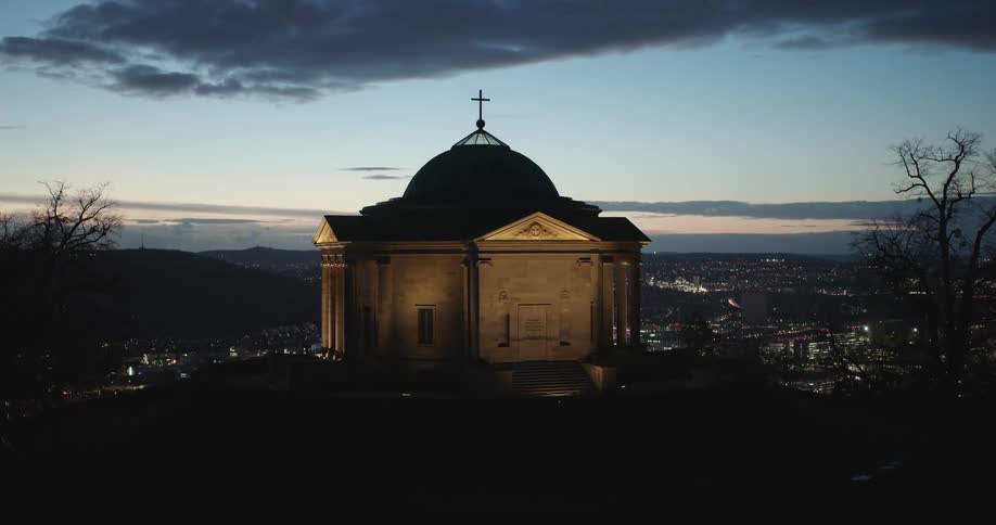 A chapel on top of a mountain lit up at sunset