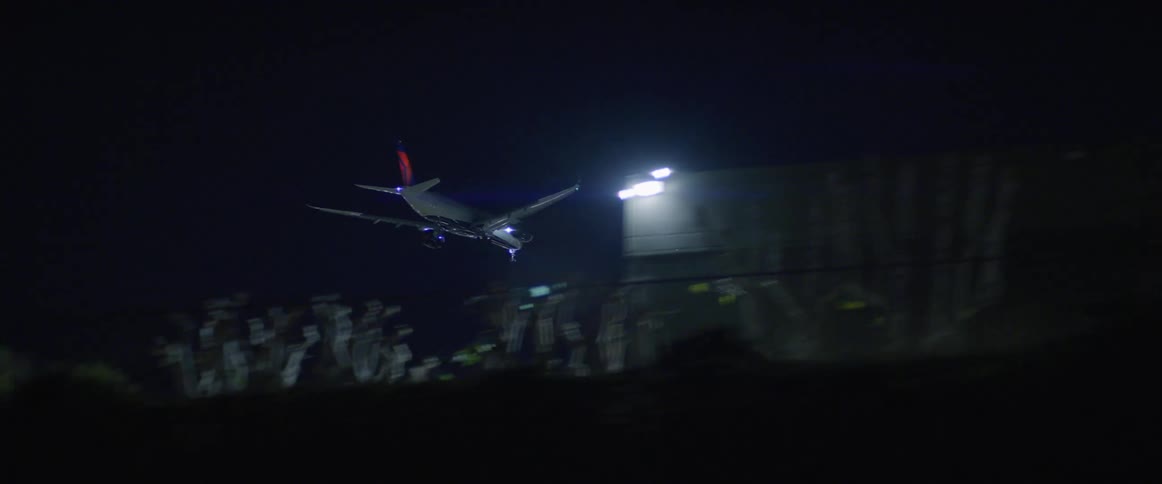 An airplane flying at night near lights and buildings