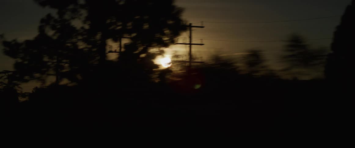 The sun hovers just above the nearby mountains in a hazy sky