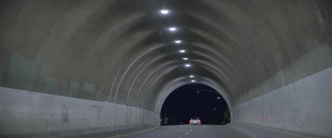 Drive though a tunnel behind a sedan at night in the city