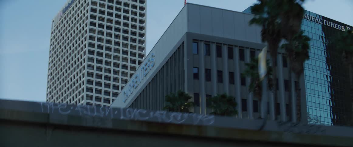 Office buildings tower over city street passing under bridge
