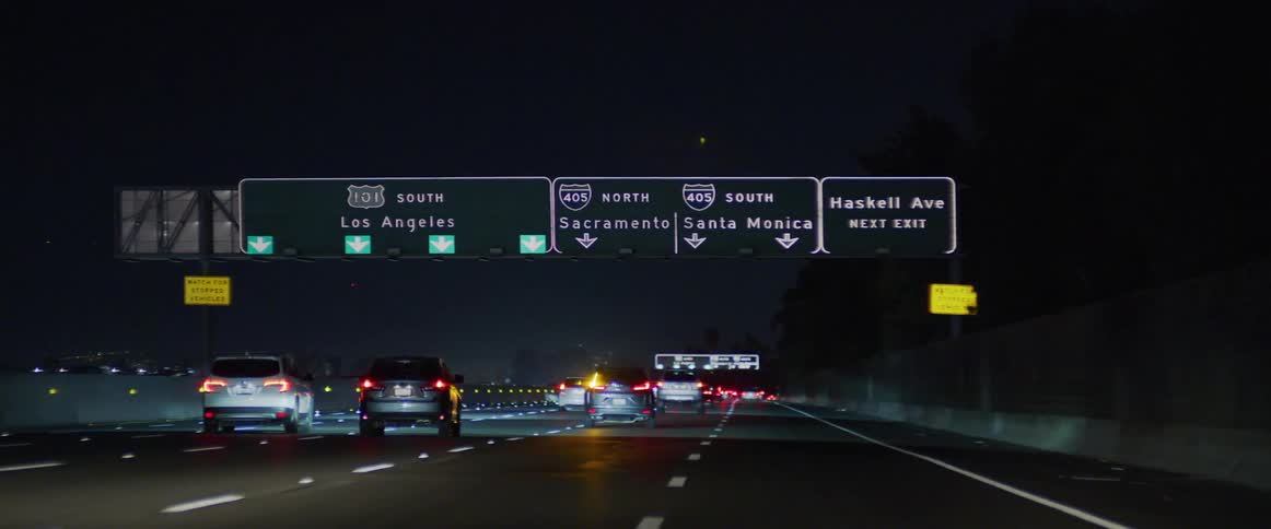 Car tail lights glow in the darkness as they move on a busy freeway at night