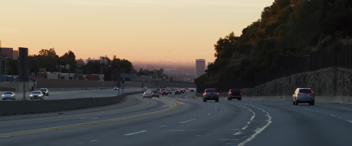 Cars driving on a highway near the city at sunset