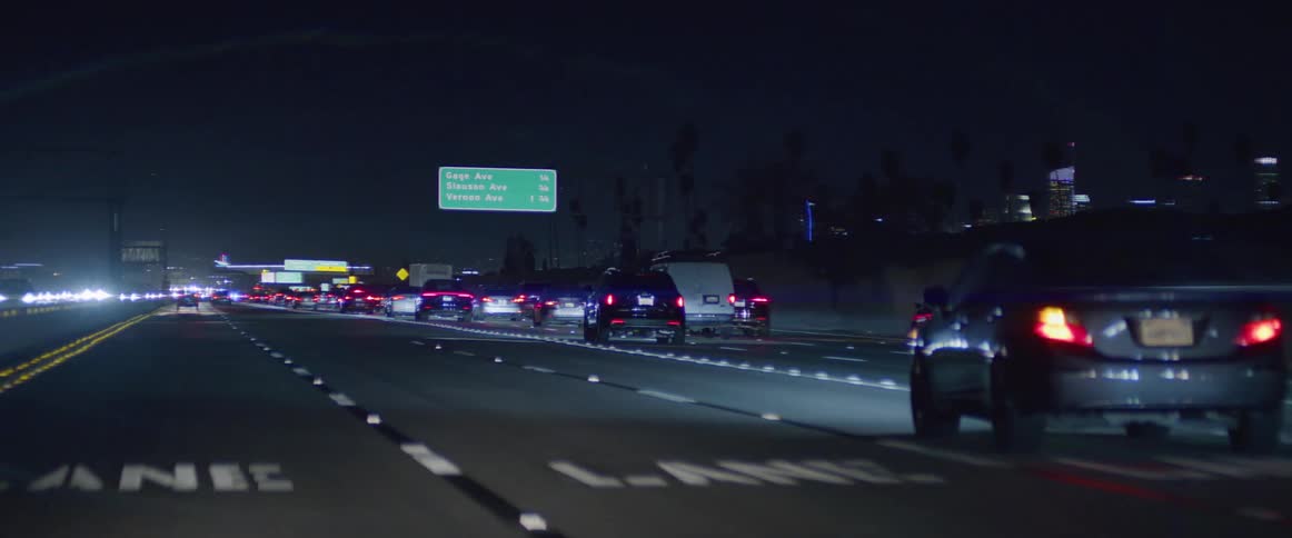 Vehicle changes lanes while driving along highway at night with skyline in the background
