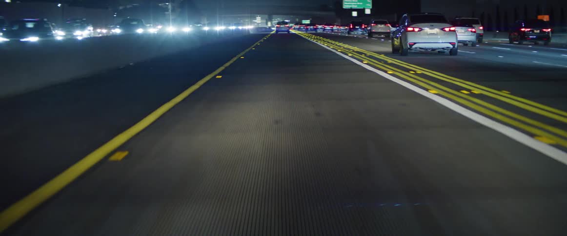 An asphalt street at night and several cars passing by