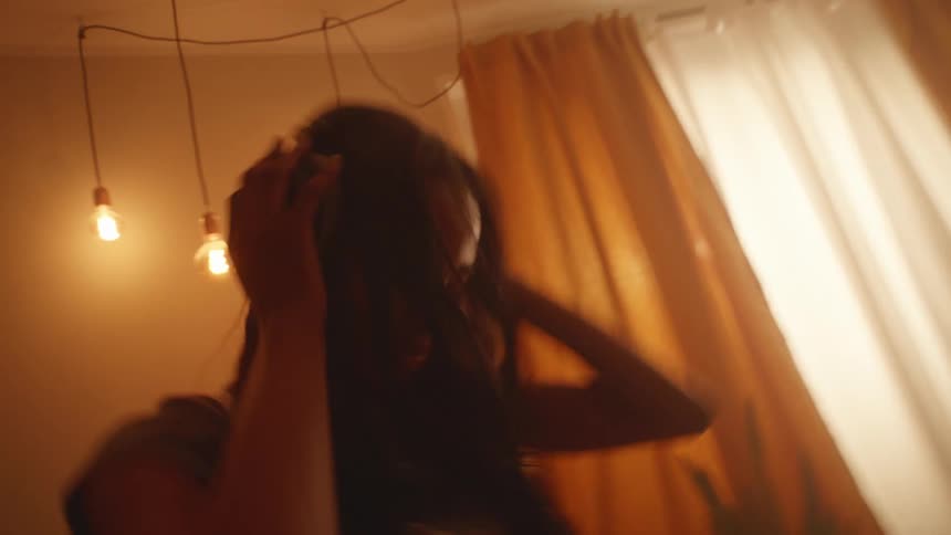 Young woman dances at home listening to music