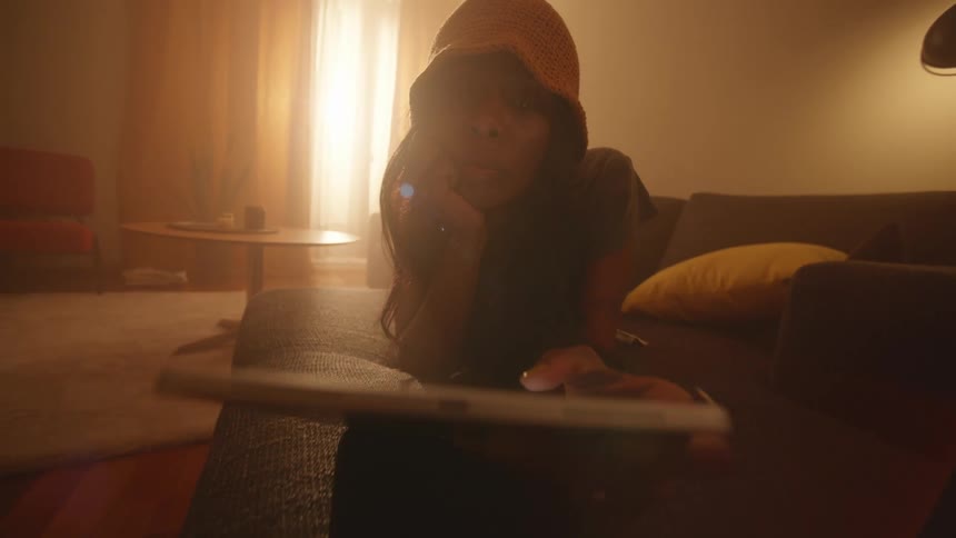 A young woman lounges on a couch while browsing her phone
