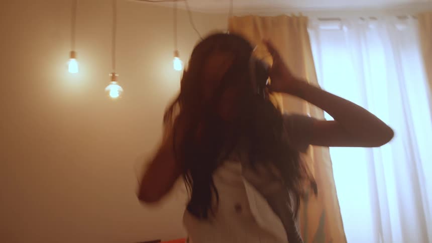 Happy woman listening to music dances at home