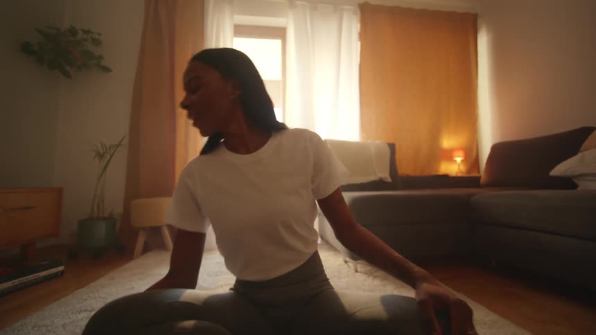 Woman doing yoga in the living room checks up her phone