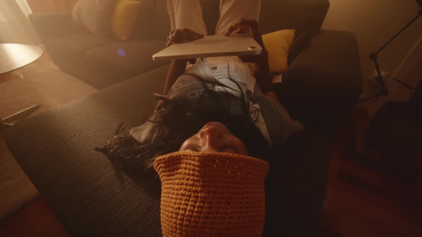 Young woman resting on the couch has fun with a tablet