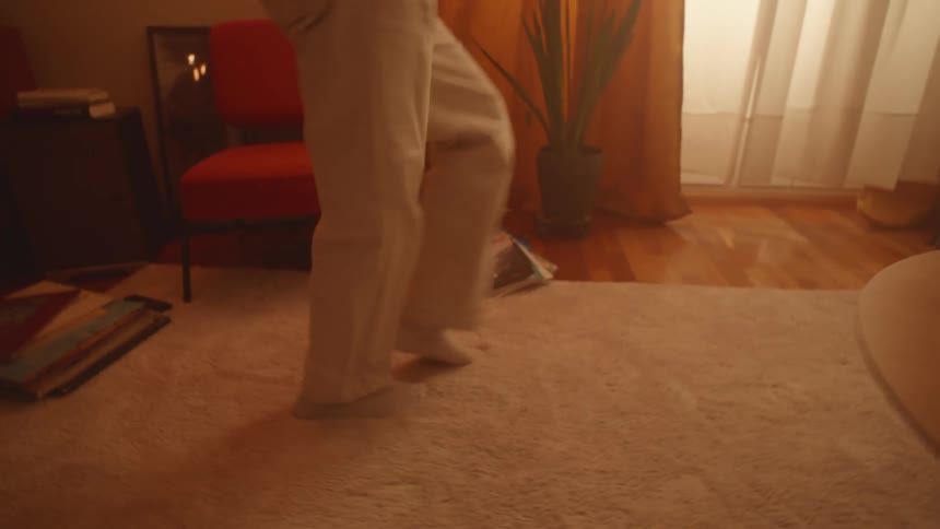 Young happy woman dances while listening to music at home