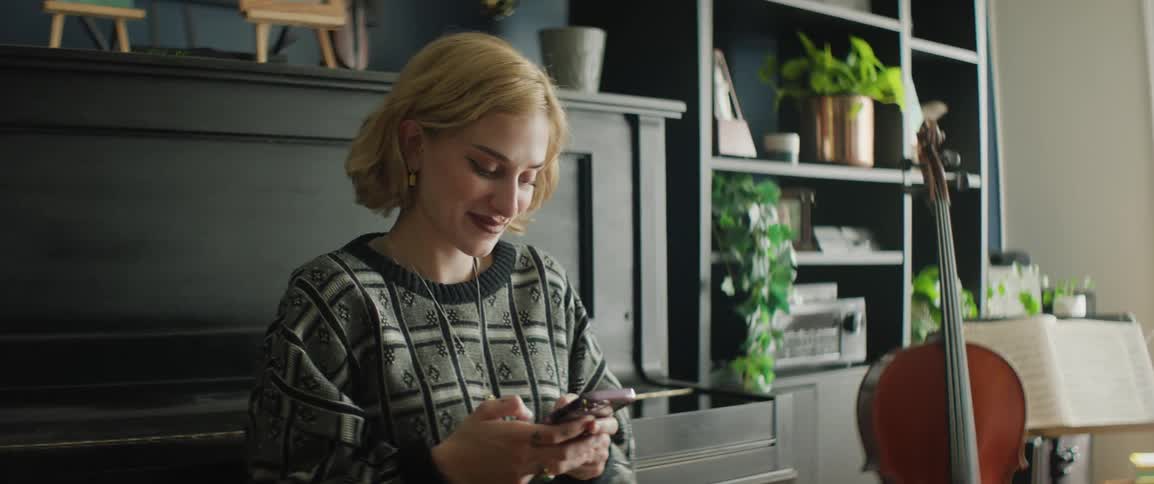 Musician sitting next to a piano texting on her phone