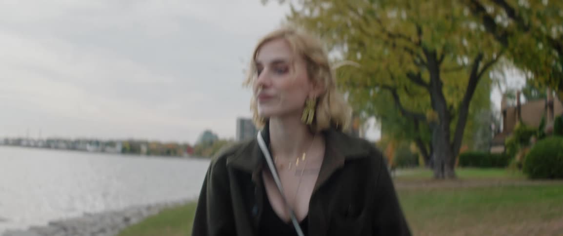 A clip of a young lady walking on a path by the lake shore