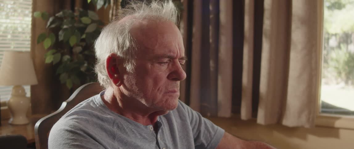 A sad man at the table putting his cap on his head