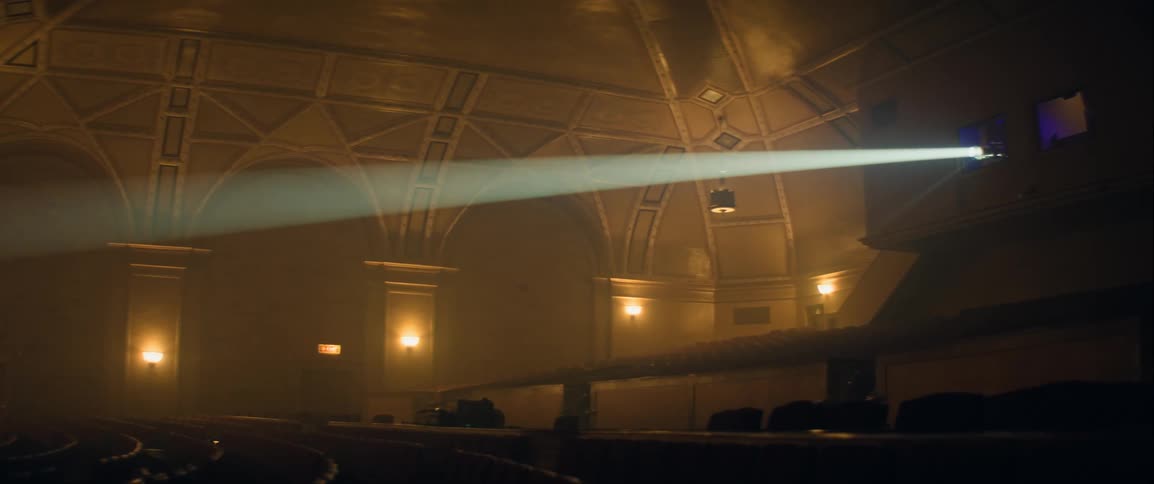 An empty theater is shown with a large spotlight beam cutting through