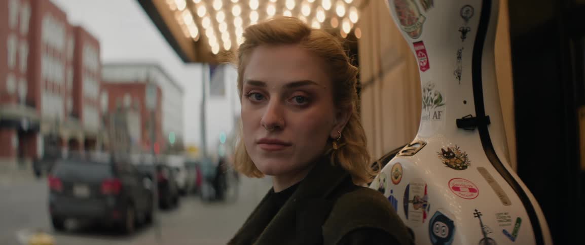 Portrait of a concert cellist standing outside the theater carrying her instrument case