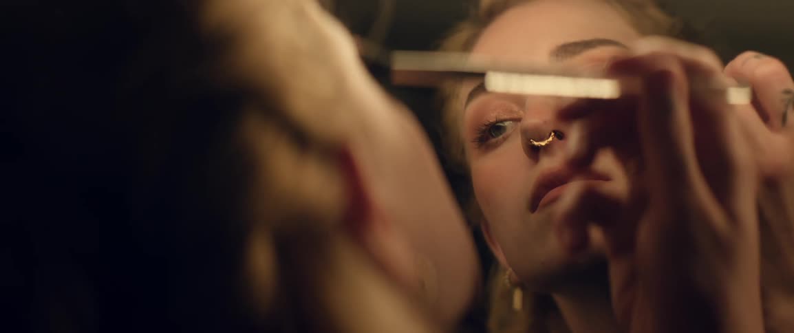 Woman applies makeup in a dressing room while looking at the mirror