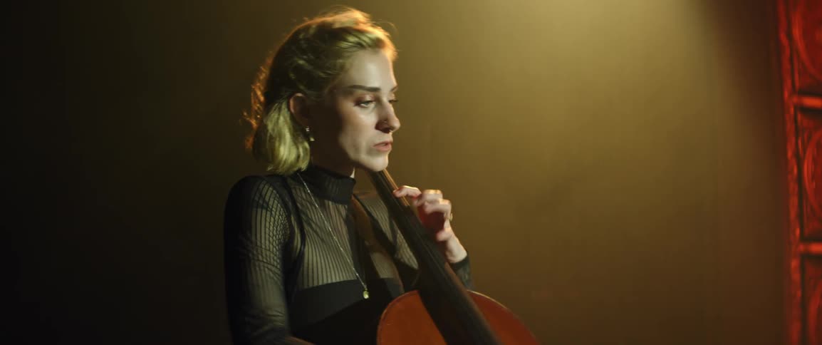 Inspired musician plays the cello on stage in a golden light