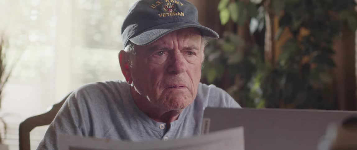 Elderly man compares spreadsheet to laptop screen then stares frowning