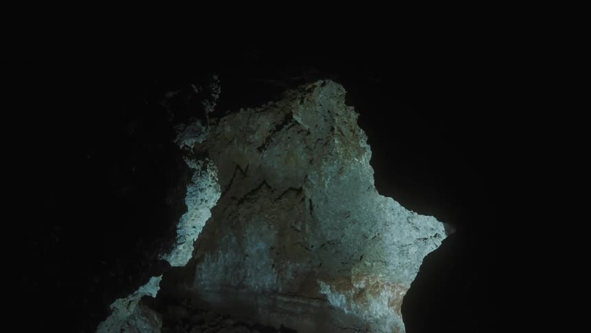 Light shines onto stalagmite in dark cave