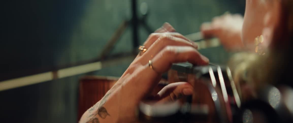 Birds eye close up view of a woman playing cello with her fingers and bow