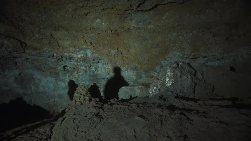 Interior of a dark cave with people walking in it