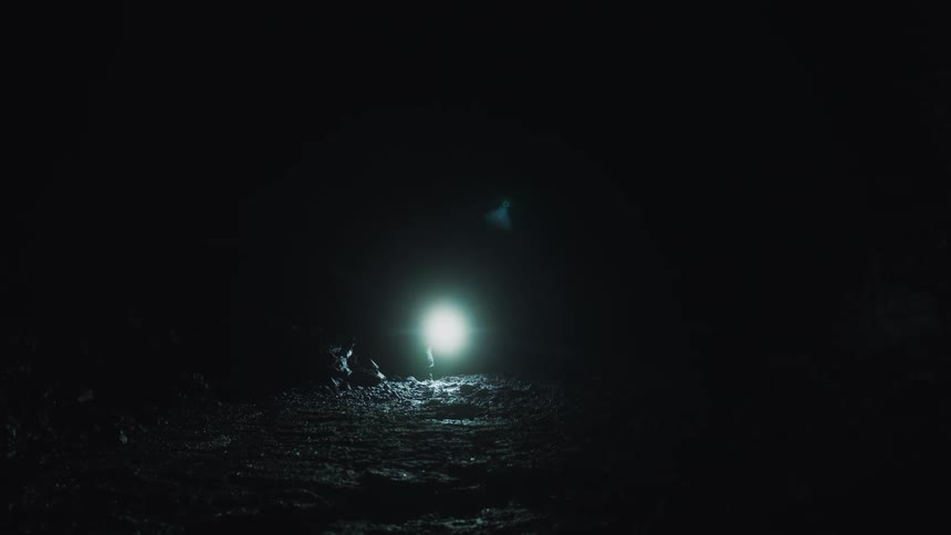 A person walking in a dark cave with a flashlight