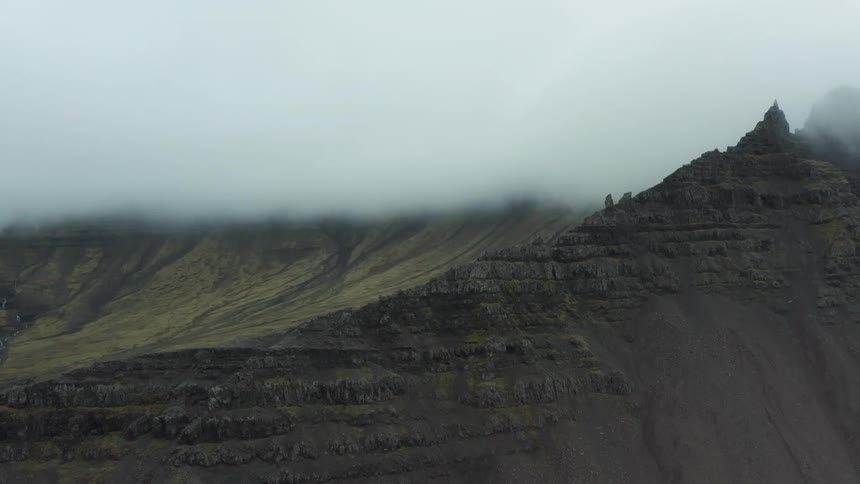Aerial view of a misty rugged mountain under clouds
