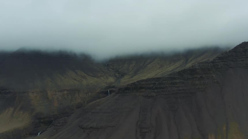 Aerial view of a misty rugged mountain under clouds