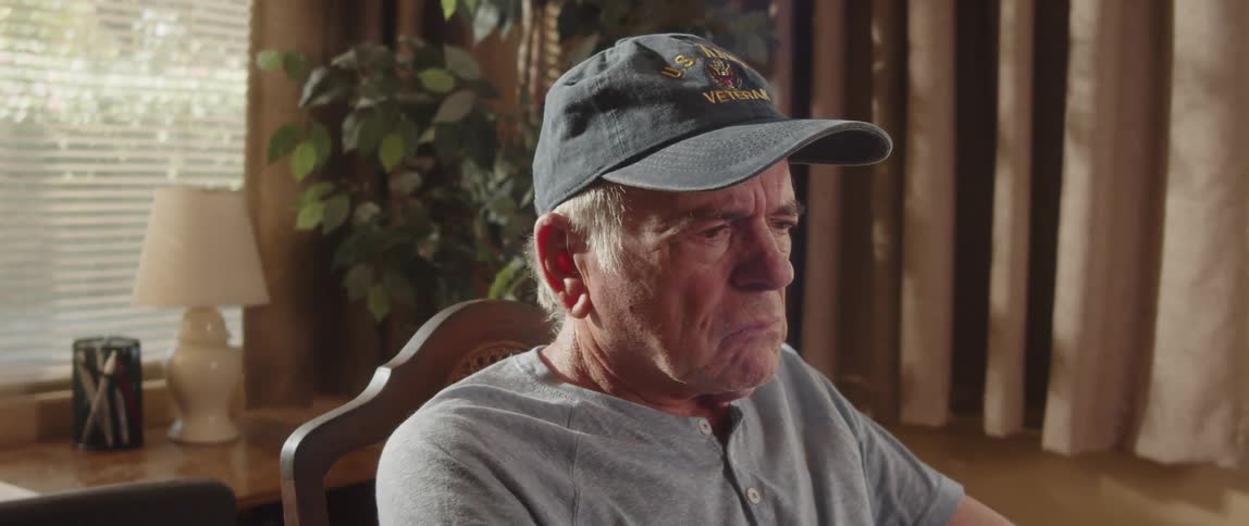 Confused elderly man sitting at home wears a baseball cap