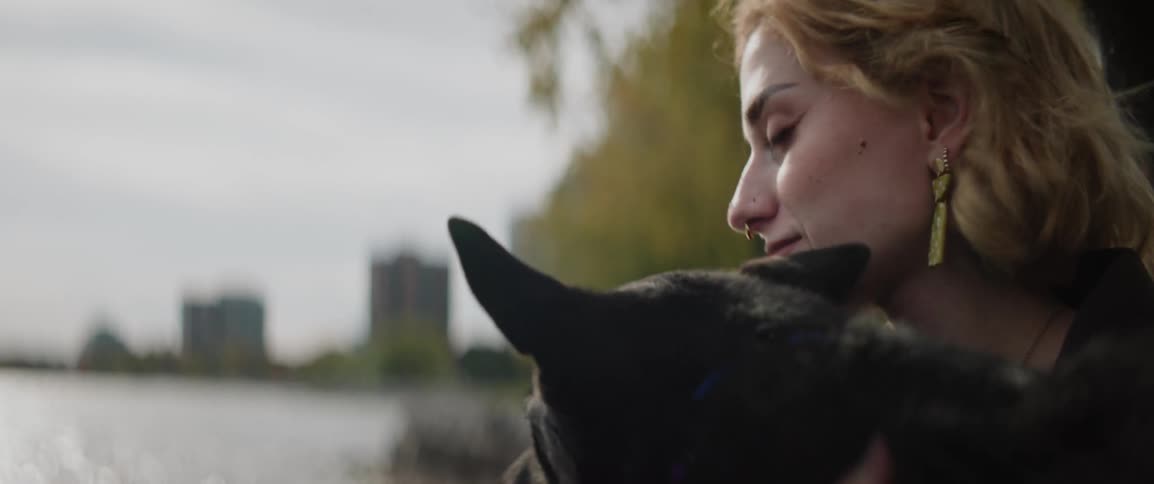 Closeup of a woman petting a dog in a waterfront park