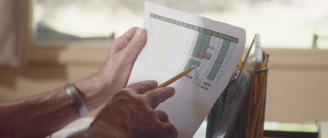 A person holding a document and twirling a pencil in their fingers