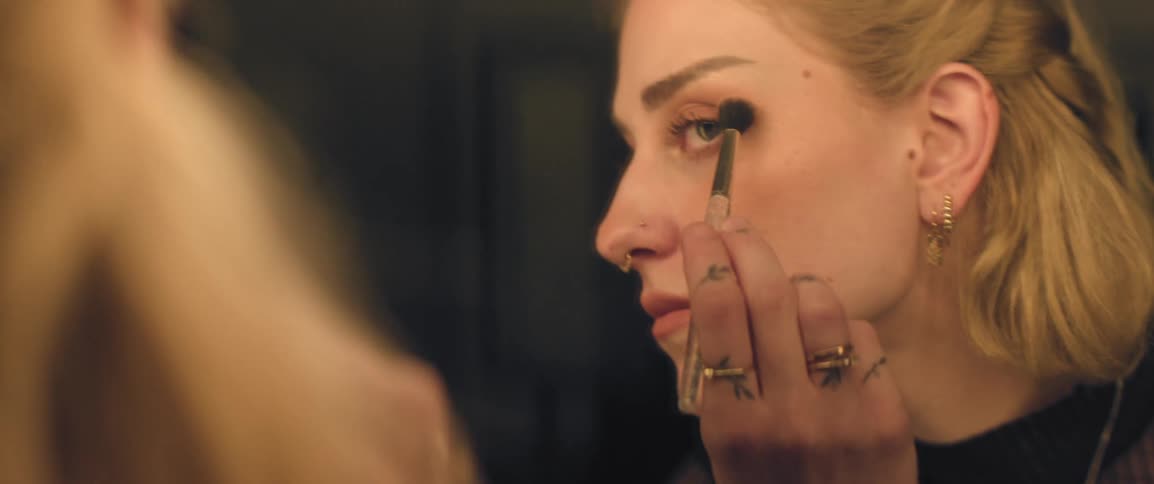 Woman applying makeup in front of a dressing room mirror