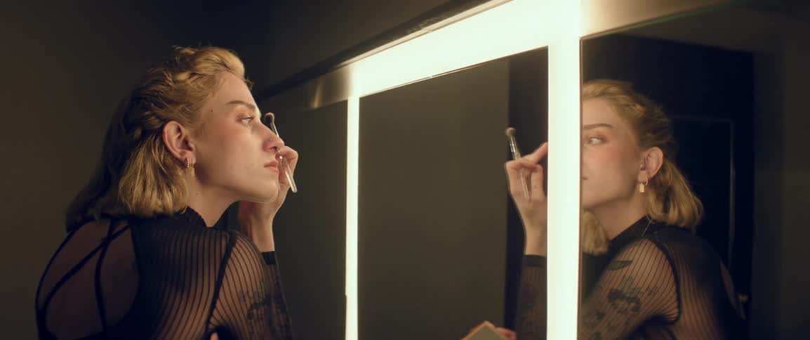 A lady applying her make up in front of the mirror in a dressing room