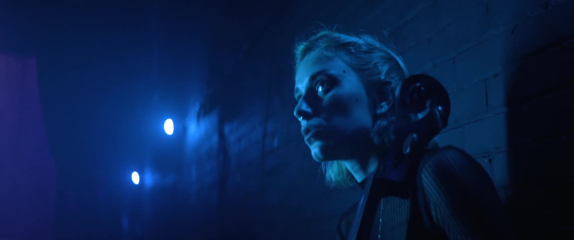 A female cellist breathes nervously backstage in a theater before a performance