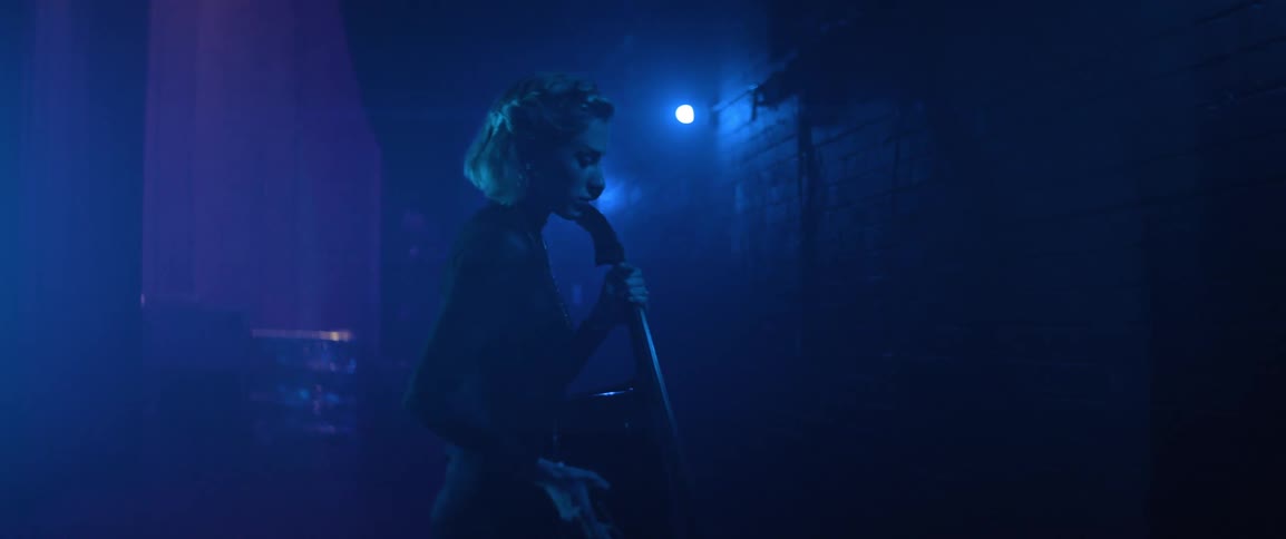 A woman with a cello in a dark amphitheater