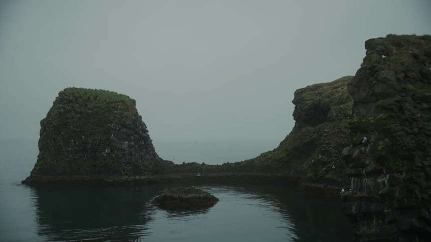 Serene misty landscape with rocy formations surrounded by calm waters