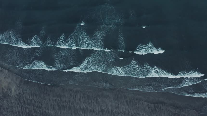 Aerial of the beach with waves crashing on the shore