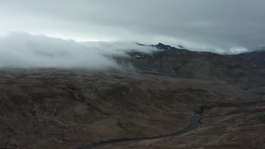 Aerial view of a misty rugged mountain under clouds
