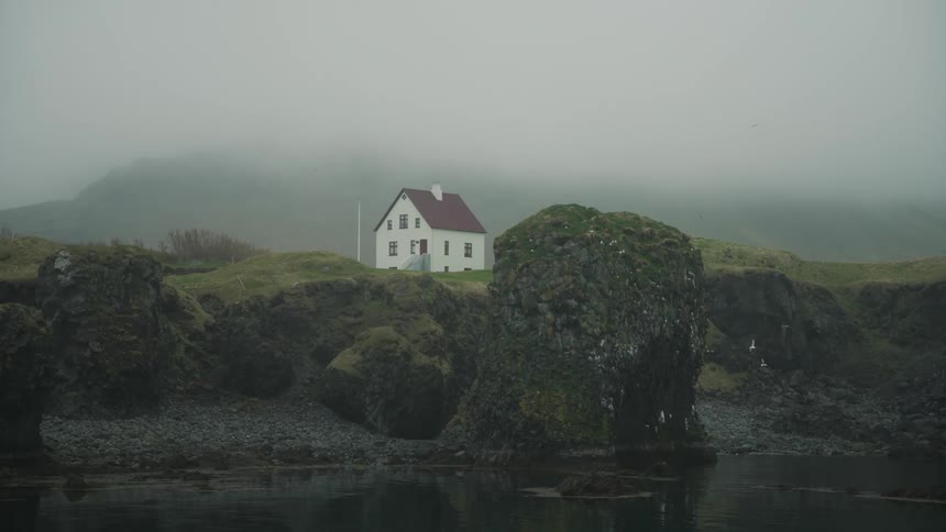 Birds fly around a remote house on the cliff